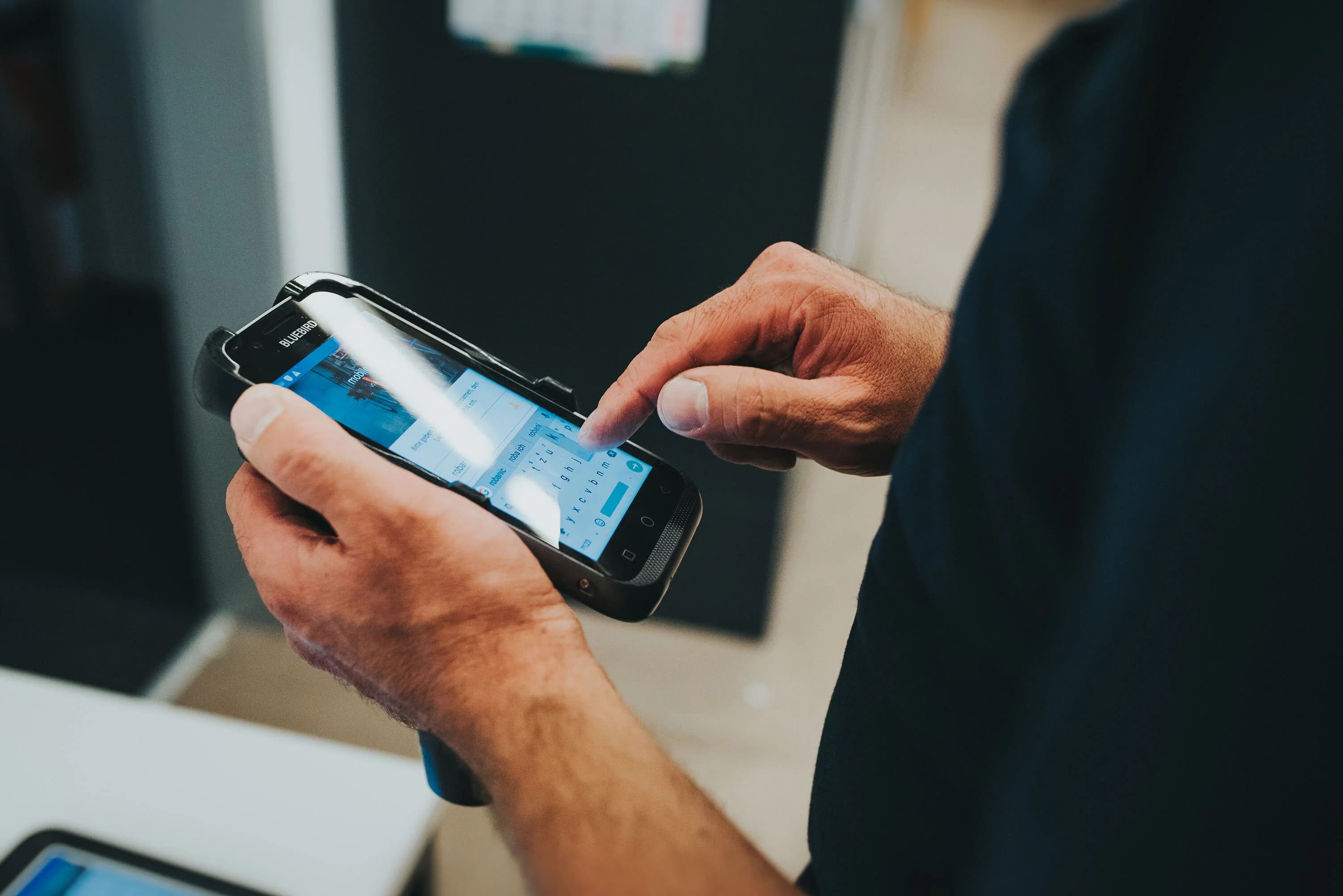 Employee at GROB-WERKE using a rugged mobile device to interact with a custom-built SAP-integrated Ontego application—supporting efficient, paperless production processes like goods receipts and order confirmations in a modern manufacturing environment.